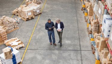 Warehouse supervisor walking and talking with senior manager